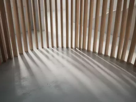 Ein minimalistischer, heller Innenraum mit vertikalen Schattenwürfen auf einem Betonboden, die eine ruhige, zeitlose Atmosphäre erzeugen. - Foto: über boerse-global.de