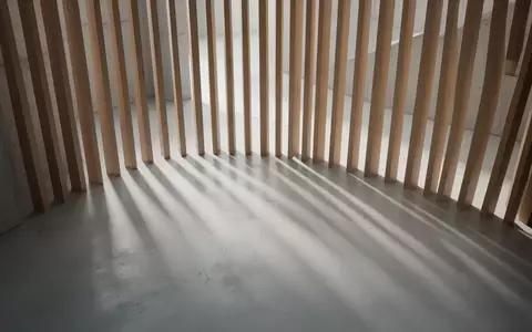 Ein minimalistischer, heller Innenraum mit vertikalen Schattenwürfen auf einem Betonboden, die eine ruhige, zeitlose Atmosphäre erzeugen. - Foto: über boerse-global.de