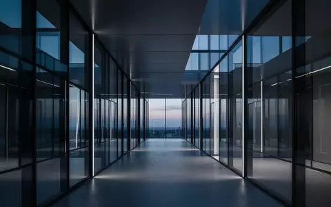 Ein minimalistischer Flur in einem modernen Bürogebäude mit geometrischen Linien und blauem Umgebungslicht. - Foto: über boerse-global.de