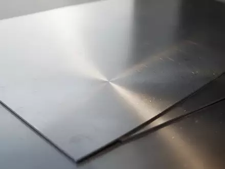 Nahaufnahme einer gebürsteten Edelstahloberfläche mit feinen Lichtreflexionen auf der glatten Metallstruktur. - Foto: über boerse-global.de