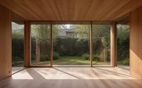Ein minimalistischer, lichtdurchfluteter Innenraum eines Holzbungalows mit Blick in einen Garten. - Foto: über boerse-global.de
