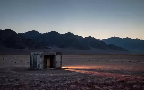 Eine weite, unberührte Wüstenlandschaft mit einer einsamen, minimalistischen Betonstruktur in der Abenddämmerung. - Foto: über boerse-global.de