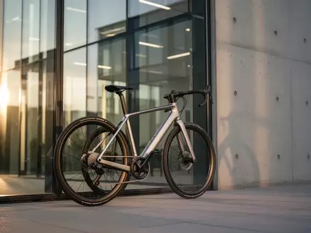 Modernes Fahrrad lehnt vor einem Bürogebäude aus Glas und Beton bei Sonnenlicht. - Foto: über boerse-global.de