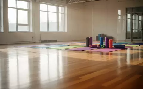 Ein heller, minimalistischer Gymnastikraum mit Holzboden, auf dem ordentlich aufgerollte Yogamatten und Schaumstoffrollen liegen. - Foto: über boerse-global.de