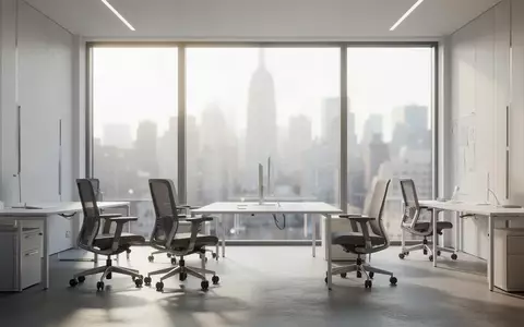 Ein minimalistisch eingerichteter, heller Büroraum mit großen Fenstern und Blick auf eine Stadt bei natürlichem Licht. - Foto: über boerse-global.de