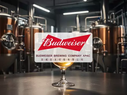Nahaufnahme eines goldenen Getränks in einem Glas vor einem unscharfen industriellen Hintergrund einer Brauerei. - Foto: über boerse-global.de