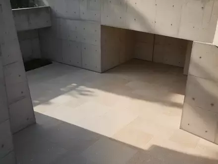 Architektonische Aufnahme eines modernen Betongebäudes mit geometrischem Schattenspiel in einem ruhigen Innenhof. - Foto: über boerse-global.de