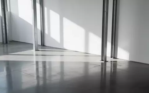 Ein minimalistischer, moderner Innenraum mit poliertem Betonboden und geometrischen Schattenwürfen. - Foto: über boerse-global.de