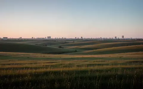 Weite, unbebaute Wiesenflächen und Felder in der Dämmerung, die das Potenzial für ein Stadtentwicklungsprojekt verdeutlichen. - Foto: über boerse-global.de