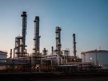 Industrielle Raffinerie mit großen Destillationstürmen und Rohrleitungen bei Dämmerung. - Foto: über boerse-global.de