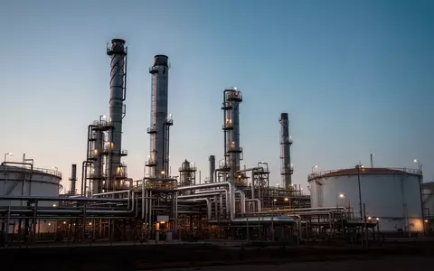 Industrielle Raffinerie mit großen Destillationstürmen und Rohrleitungen bei Dämmerung. - Foto: über boerse-global.de
