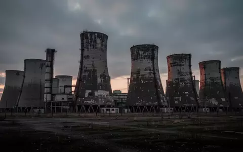 Industrielle Architektur mit großen Kühltürmen in einer kargen Landschaft bei Dämmerung. - Foto: über boerse-global.de