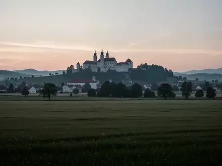 Weite, ruhige Landschaft im österreichischen Melk bei Dämmerung mit der Silhouette der Stiftskirche im Hintergrund. - Foto: über boerse-global.de