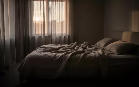 Ein ungemachtes Bett in einem spärlich beleuchteten Schlafzimmer im Morgengrauen, das eine Atmosphäre der Erschöpfung vermittelt. - Foto: über boerse-global.de