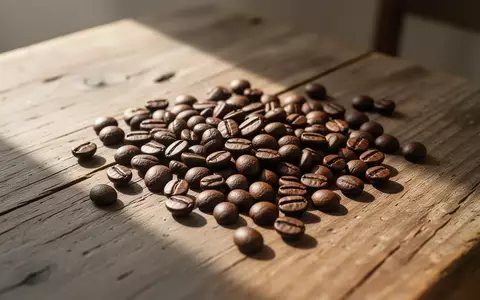 Nahaufnahme von gerösteten Kaffeebohnen auf einem hölzernen Tisch bei natürlichem Lichteinfall. - Foto: über boerse-global.de