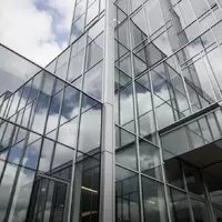 Moderne Glasfassade eines Bürogebäudes mit Spiegelungen des Himmels und architektonischen Linien. - Foto: über boerse-global.de