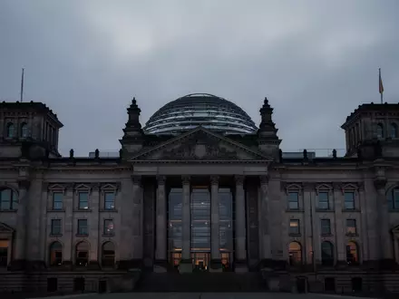 Das Reichstagsgebäude in Berlin in der Dämmerung unter einem bewölkten Himmel. - Foto: über boerse-global.de
