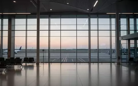 Ein minimalistischer, menschenleerer Abflugbereich an einem Flughafen in der Abenddämmerung mit Blick auf das Rollfeld. - Foto: über boerse-global.de