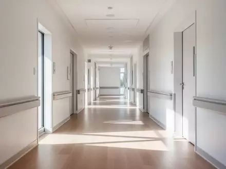 Ein heller, minimalistischer Flur in einem modernen Pflegegebäude mit natürlichem Lichteinfall und klaren architektonischen Linien. - Foto: über boerse-global.de