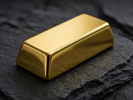Ein einzelner Goldbarren auf einer dunklen Schieferoberfläche bei sanfter, professioneller Beleuchtung. - Foto: über boerse-global.de