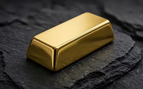 Ein einzelner Goldbarren auf einer dunklen Schieferoberfläche bei sanfter, professioneller Beleuchtung. - Foto: über boerse-global.de