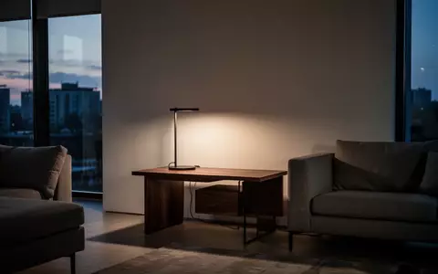 Ein minimalistisch eingerichteter Wohnraum mit gedimmtem Licht und einem modernen Beistelltisch vor einer leeren Wand. - Foto: über boerse-global.de
