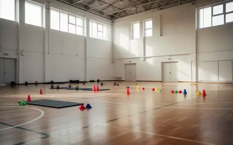Leere Sporthalle mit aufgeräumten Trainingsgeräten und hellem Hallenboden für die Vorbereitung junger Athleten. - Foto: über boerse-global.de