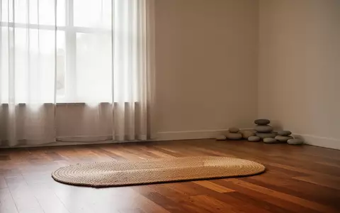 Ein minimalistisch eingerichteter Raum mit einer leeren Meditationsmatte auf einem Holzboden und sanftem Tageslicht. - Foto: über boerse-global.de