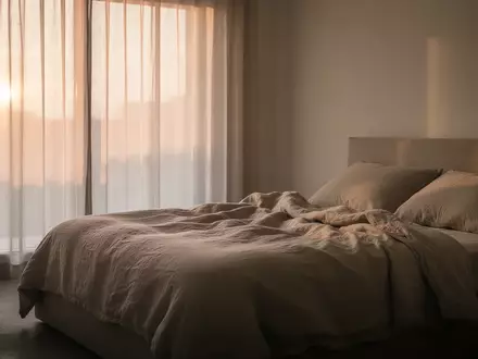 Ein ruhiges, minimalistisches Schlafzimmer bei Tagesanbruch mit weichem Licht und einem ungemachten Bett. - Foto: über boerse-global.de