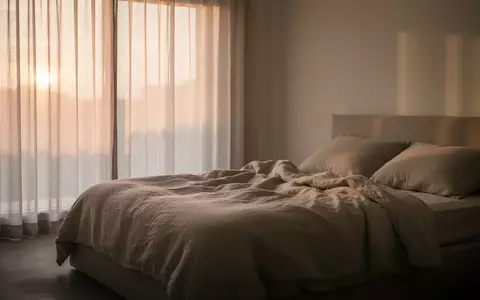 Ein ruhiges, minimalistisches Schlafzimmer bei Tagesanbruch mit weichem Licht und einem ungemachten Bett. - Foto: über boerse-global.de