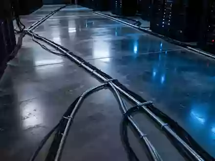 Dunkler, minimalistischer Serverraum mit kühler blauer Beleuchtung und industriellen Kabelkanälen am Boden. - Foto: über boerse-global.de