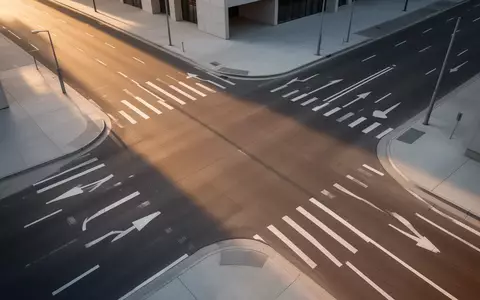 Eine moderne, leere Straßenkreuzung aus der Vogelperspektive mit klaren Fahrbahnmarkierungen bei Sonnenlicht. - Foto: über boerse-global.de