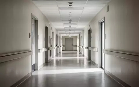 Ein minimalistischer, leerer Krankenhausflur mit neutralen Farben und klaren architektonischen Linien bei natürlichem Licht. - Foto: über boerse-global.de