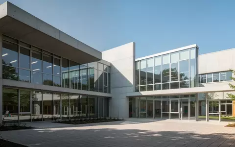 Ein moderner Schulneubau mit groĂflĂ€chigen Glasfronten und einer klaren architektonischen Gestaltung bei Tageslicht. - Foto: ĂŒber boerse-global.de