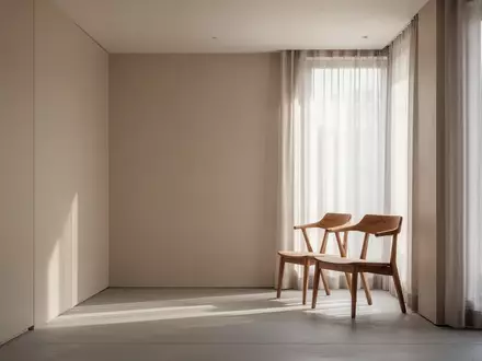 Ein minimalistisch eingerichteter, heller Raum mit einem leeren Holzstuhl vor einem Fenster mit lichtdurchlässigen Vorhängen. - Foto: über boerse-global.de