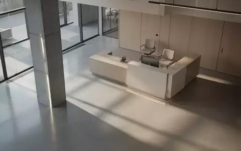 Ein minimalistischer, leerer Empfangsbereich in einem modernen Bürogebäude mit architektonischen Schatten. - Foto: über boerse-global.de