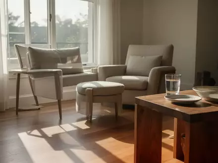 Ein helles, modern eingerichtetes Wohnzimmer mit einem bequemen Sessel in der Nähe eines Fensters bei natürlichem Lichteinfall. - Foto: über boerse-global.de