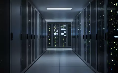 Ein leerer, düster beleuchteter Korridor in einem Rechenzentrum mit unscharfen Server-Racks im Hintergrund. - Foto: über boerse-global.de