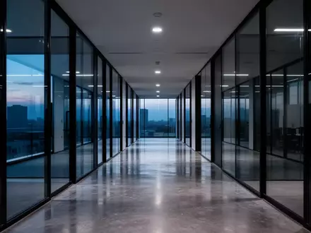 Ein minimalistischer, leerer Büroflur mit Glaswänden bei Dämmerung, der eine ruhige und professionelle Atmosphäre vermittelt. - Foto: über boerse-global.de