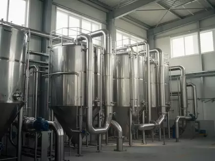 Industrielle Verarbeitungsanlage für Lebensmittel mit Edelstahlsilos in einer sauberen Lagerhalle. - Foto: über boerse-global.de
