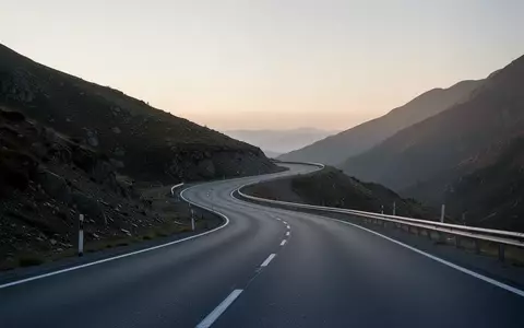 Eine leere, geschwungene Landstraße bei Dämmerung, die die Veränderung in der Kfz-Versicherungslandschaft symbolisiert. - Foto: über boerse-global.de