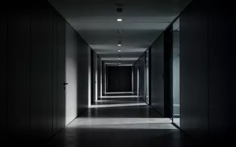 Ein minimalistischer, dunkel beleuchteter moderner Büroflur mit langen Schatten und architektonischen Linien. - Foto: über boerse-global.de