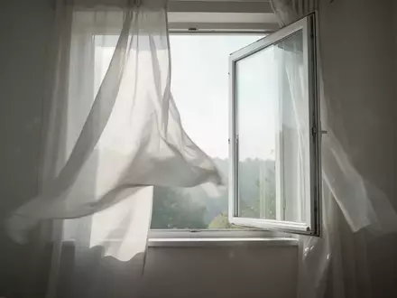 Ein offenes Fenster in einem hellen, minimalistischen Raum, durch das frische Luft strömt, symbolisiert eine gute Raumluftqualität. - Foto: über boerse-global.de