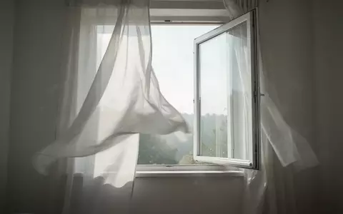 Ein offenes Fenster in einem hellen, minimalistischen Raum, durch das frische Luft strömt, symbolisiert eine gute Raumluftqualität. - Foto: über boerse-global.de