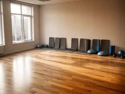 Ein heller, minimalistischer Ăbungsraum mit Holzboden und leeren Sportmatten fĂŒr PrĂ€ventionskurse. - Foto: ĂŒber boerse-global.de