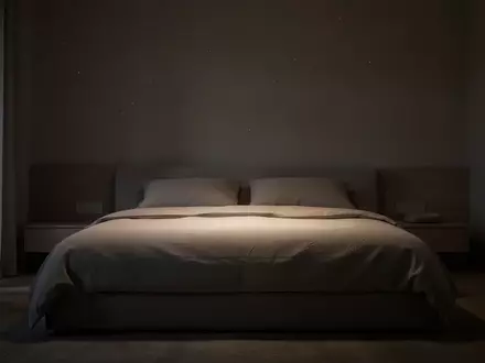 Ein minimalistisches, in sanftes Licht getauchtes Schlafzimmer bei Nacht, das eine ruhige und erholsame Umgebung symbolisiert. - Foto: über boerse-global.de