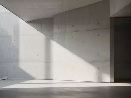 Ein minimalistischer, lichtdurchfluteter moderner Innenraum mit klaren geometrischen Linien und weichen Schatten auf einer Betonwand. - Foto: über boerse-global.de