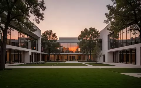 Ein moderner, minimalistischer Campus-Innenhof mit geometrischer Architektur und großen Glasfassaden bei Dämmerung. - Foto: über boerse-global.de