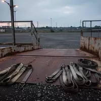 Eine leere, industrielle Ladefläche mit aufgerollten Spanngurten auf einem Kiesplatz bei Dämmerung. - Foto: über boerse-global.de