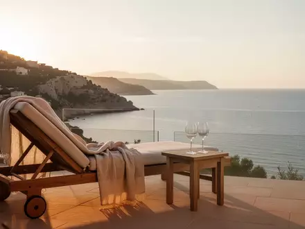 Eine sonnige Terrasse mit Blick auf das Meer bei Sonnenuntergang, die eine entspannte Atmosphäre im Ruhestand symbolisiert. - Foto: über boerse-global.de